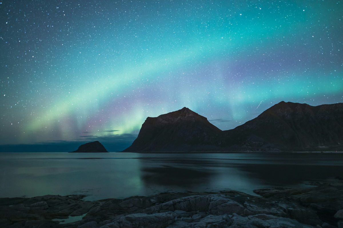 Green northern lights over the mountains of Lofoten at night