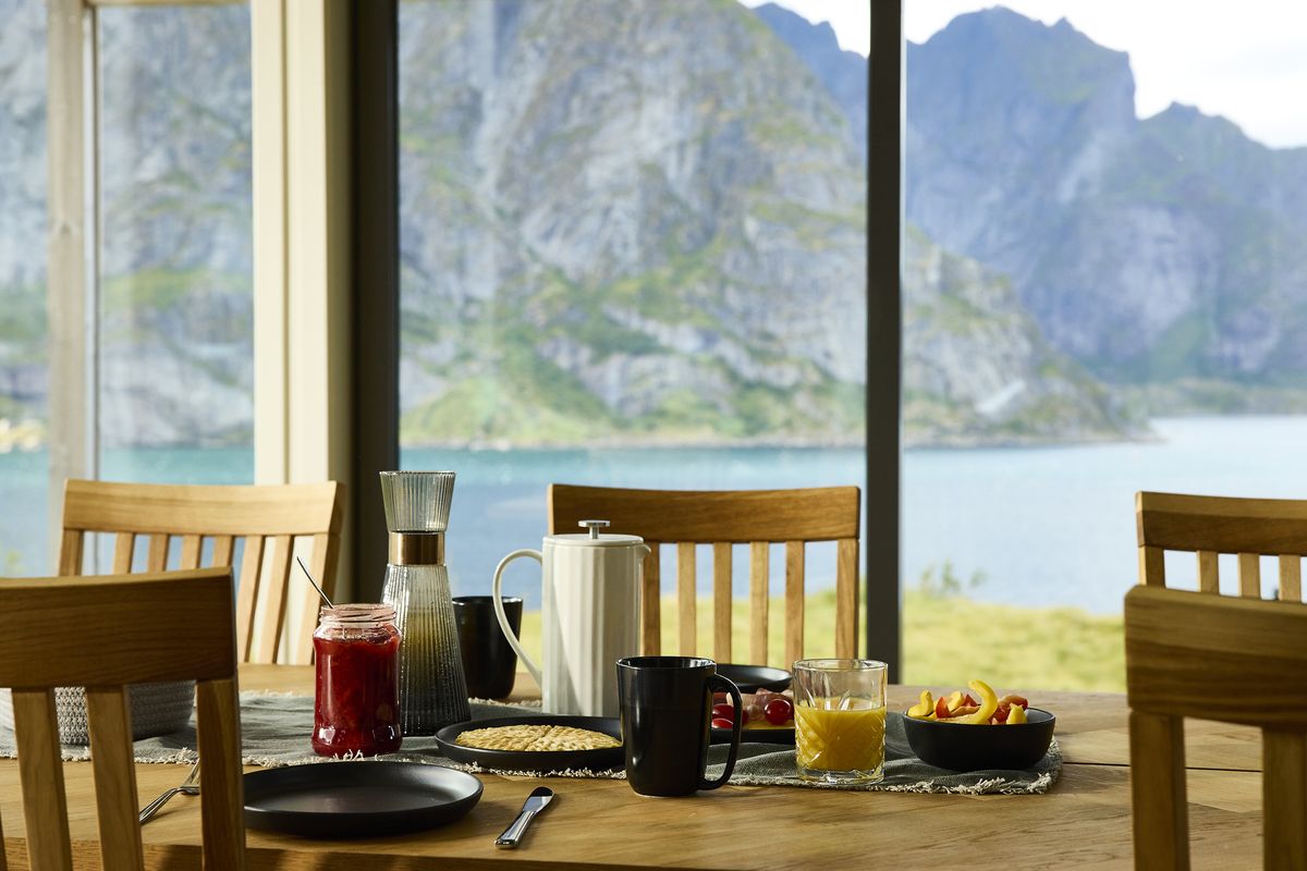 Breakfast table by the window in Reine with green mountains and the fjord outside