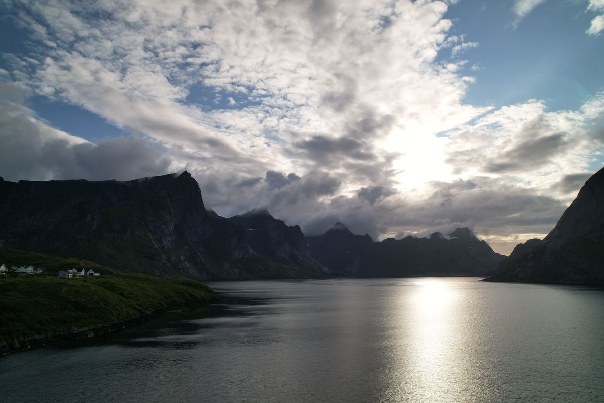 Sunlight breaking through clouds onto the fjord near Reine