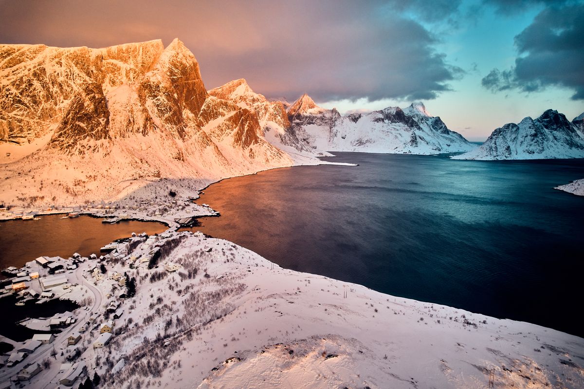 Golden morning light on the snowy peaks above the fjord at Reine, seen from the air