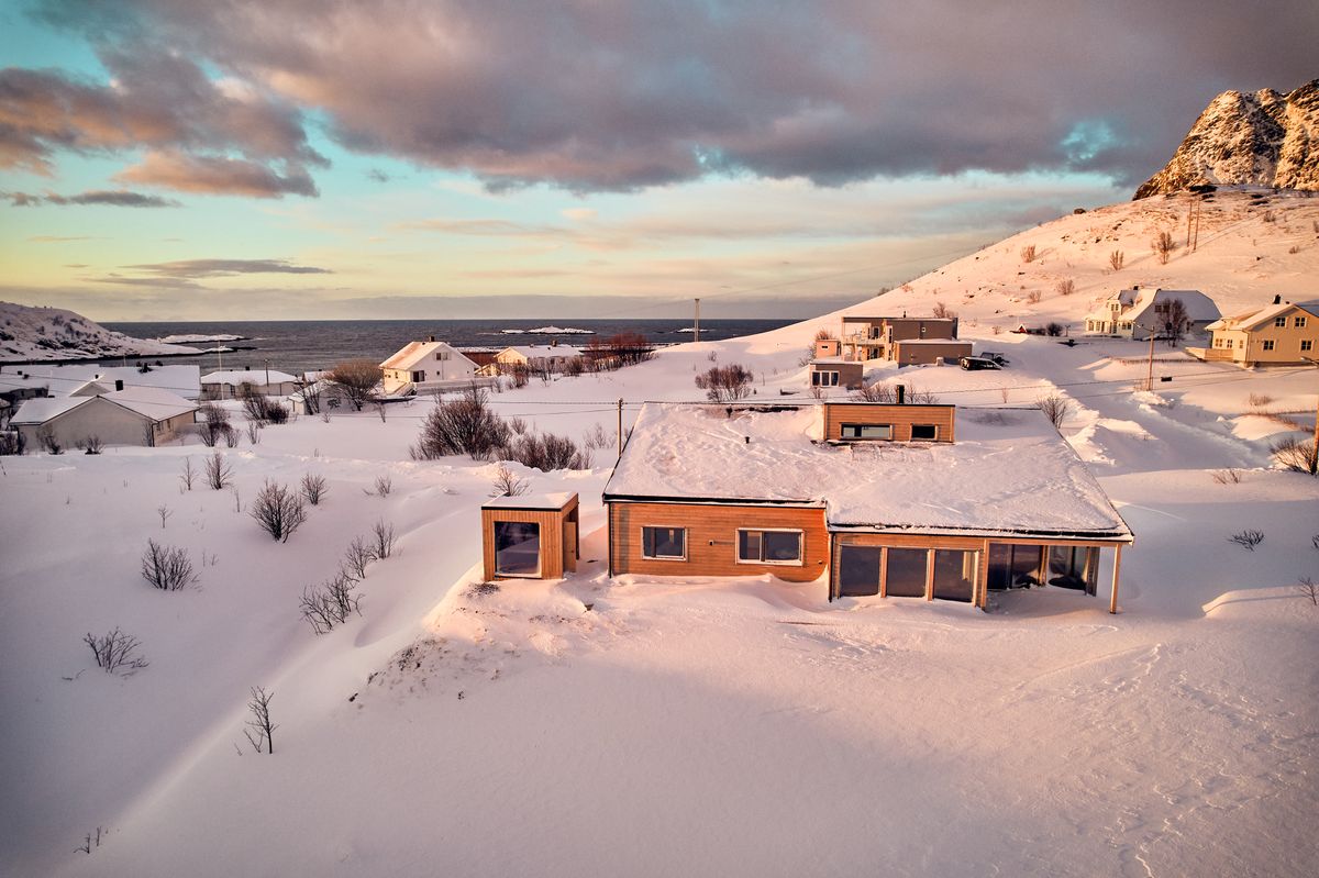 Our house in Reine in deep snow, seen from the air with the mountains behind