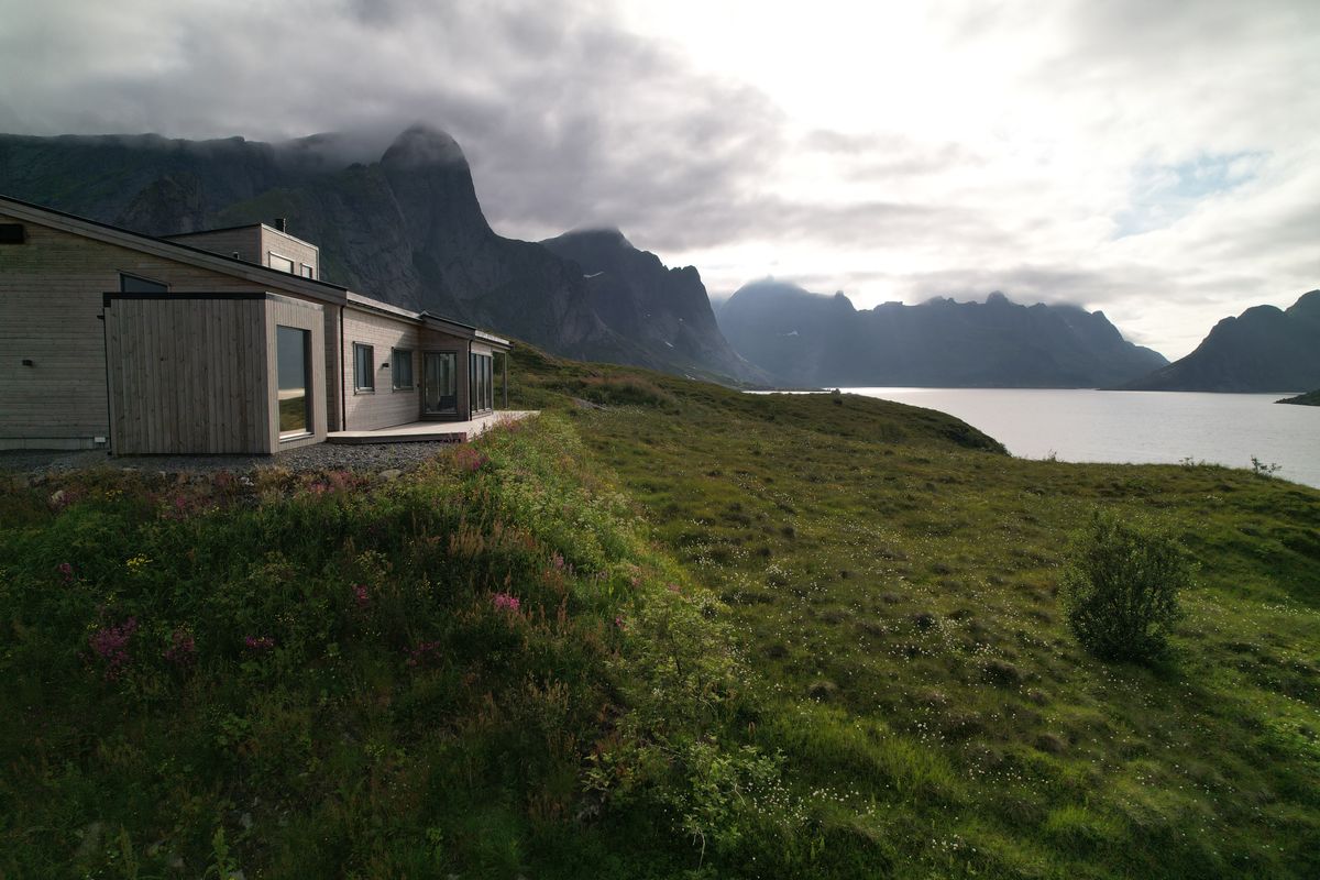 The Reine house in summer on a green meadow above the fjord