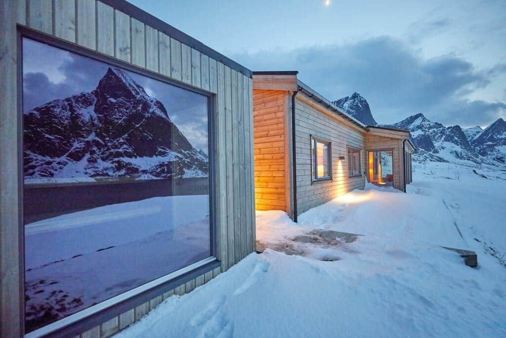 The separate sauna hut with its big window in the snow, the house behind it