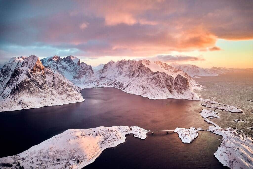 Wide view over Reinefjord at sunrise, snowy peaks all around and our house on the larger island on the left